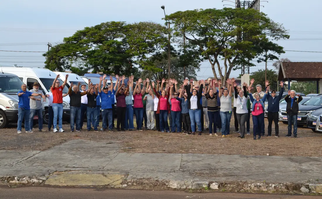 Equipe de cooperados da COOTTRAFOZ reunida em frente à frota de vans em Foz do Iguaçu